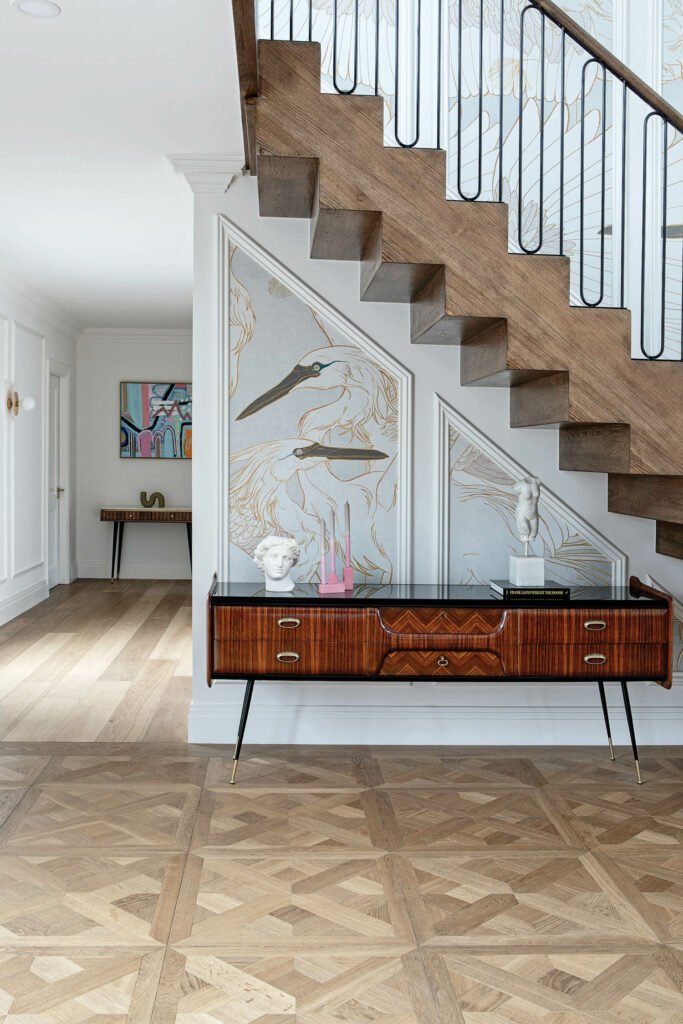 a vintage sideboard sits under the stairs in the entry hall