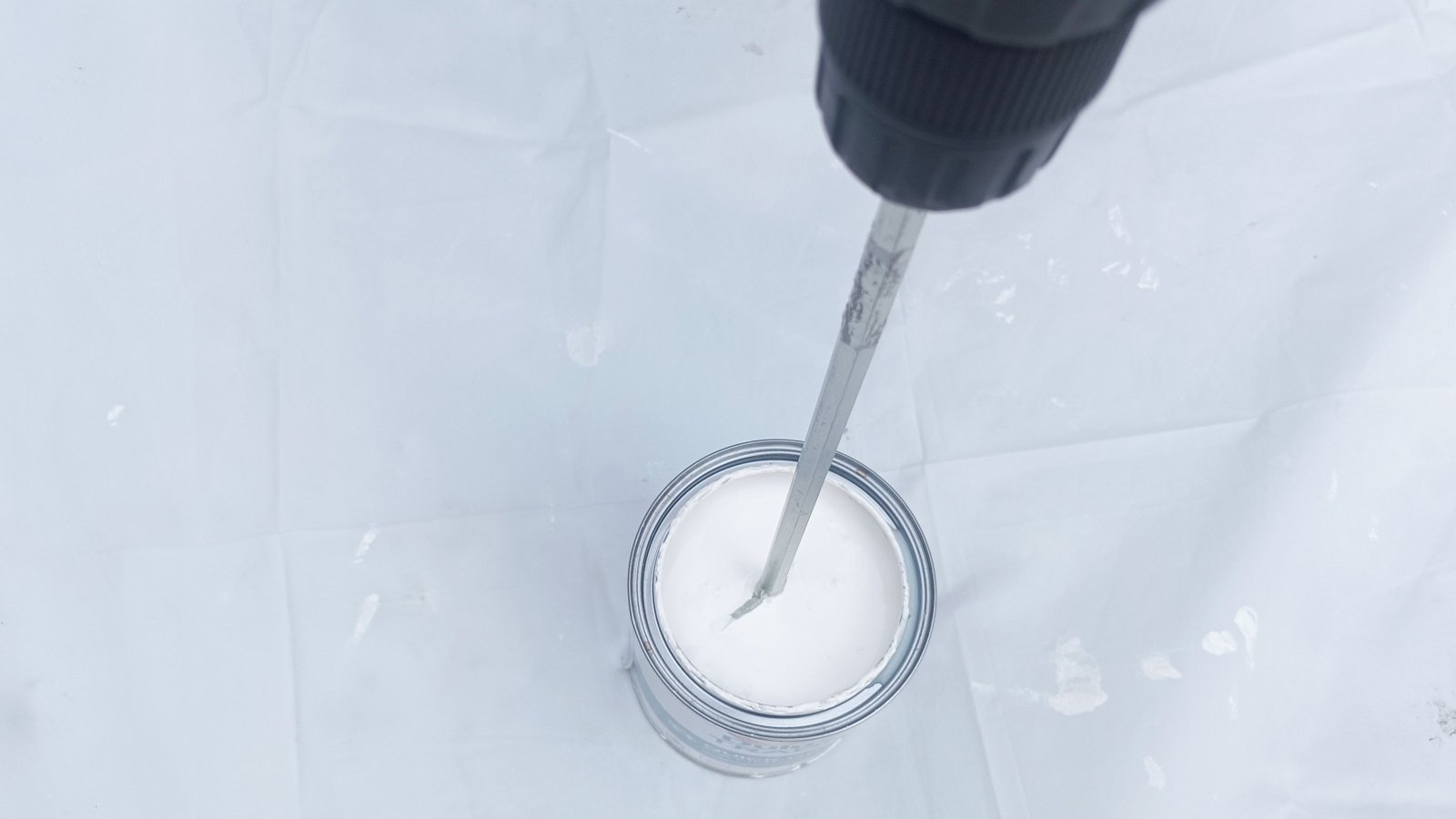 Top down shot of drill paddle mixer mixing paint on white background