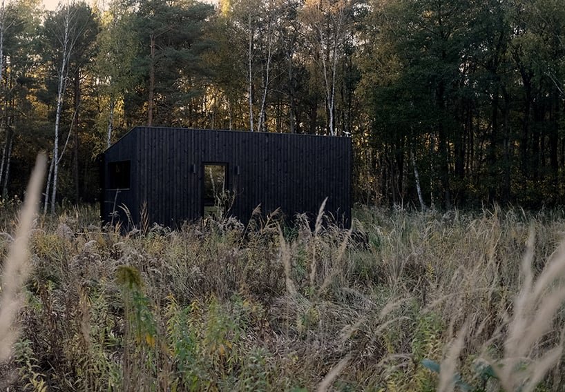 darkened plywood coats REDUKT's mobile tiny cabin offering an off-grid retreat