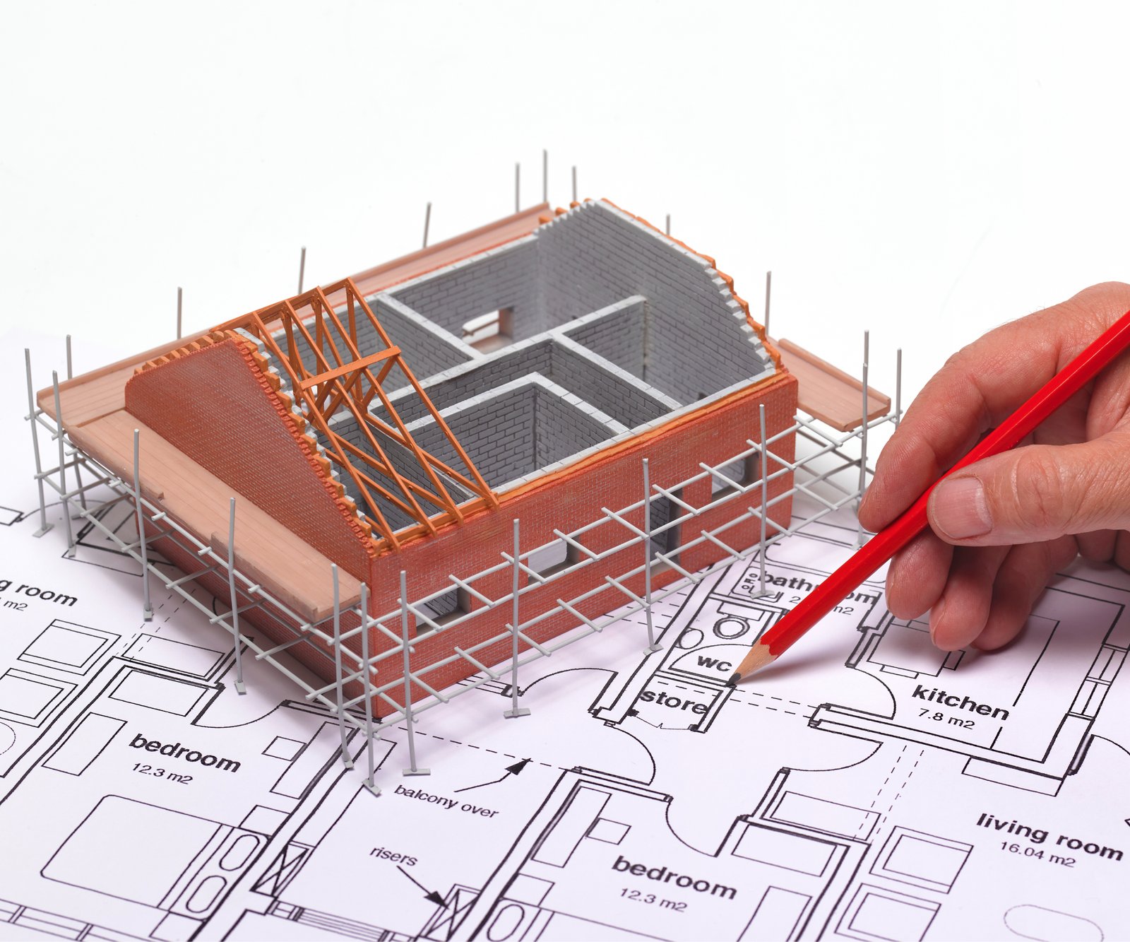 model of 2 house placed on plans with hand annotating marks with a pencil