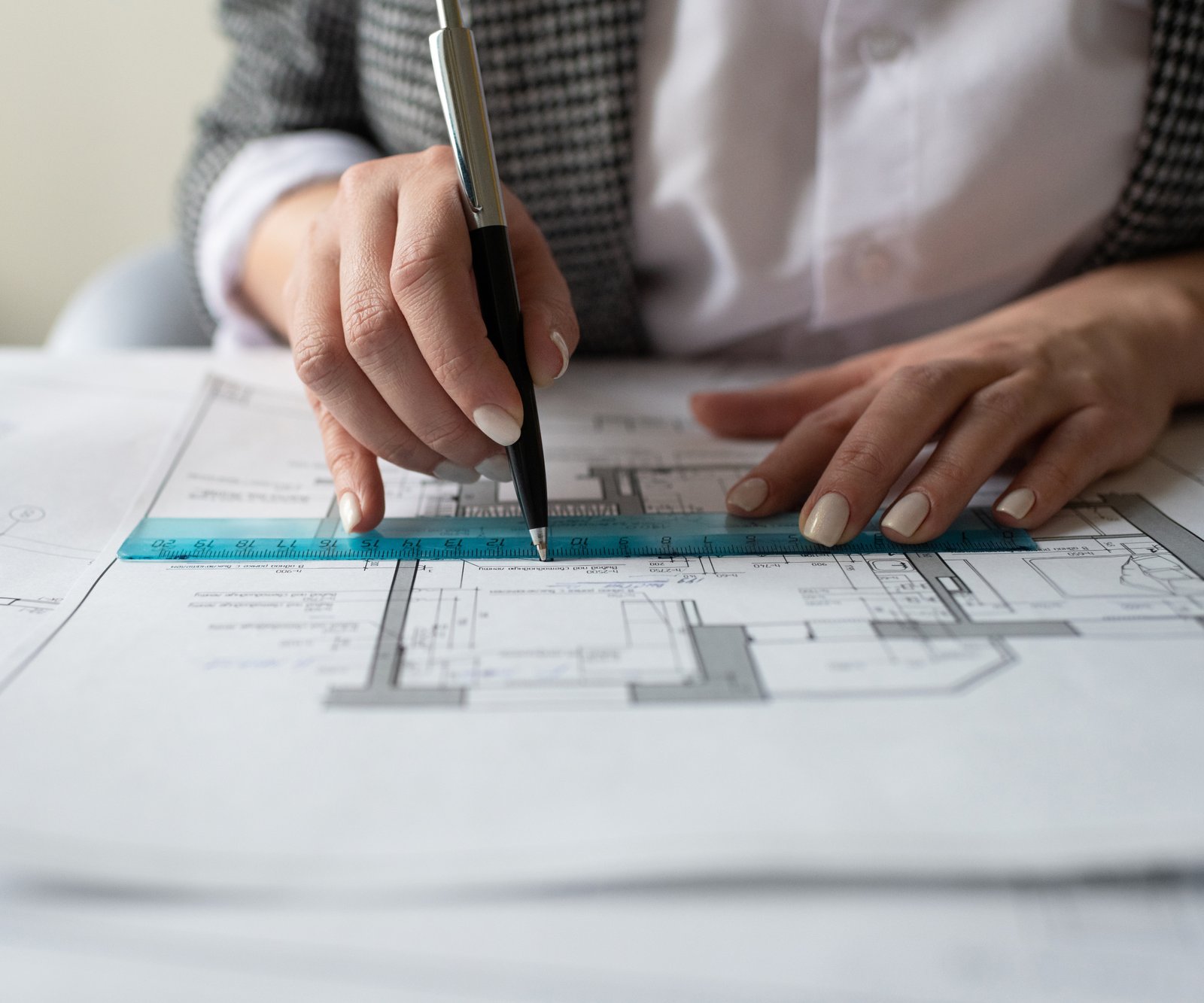 woman's hand holding compass over set of architetural plans