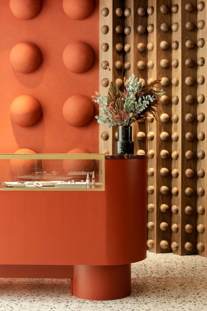 detail of the red jewelry consoles and wall behind with raised dot patterns