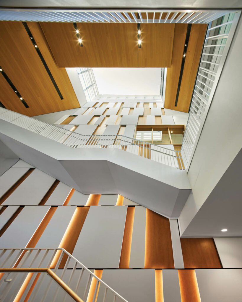 a striped wall with a white staircase overlooks floors in The Graham Athletics & Wellness Center