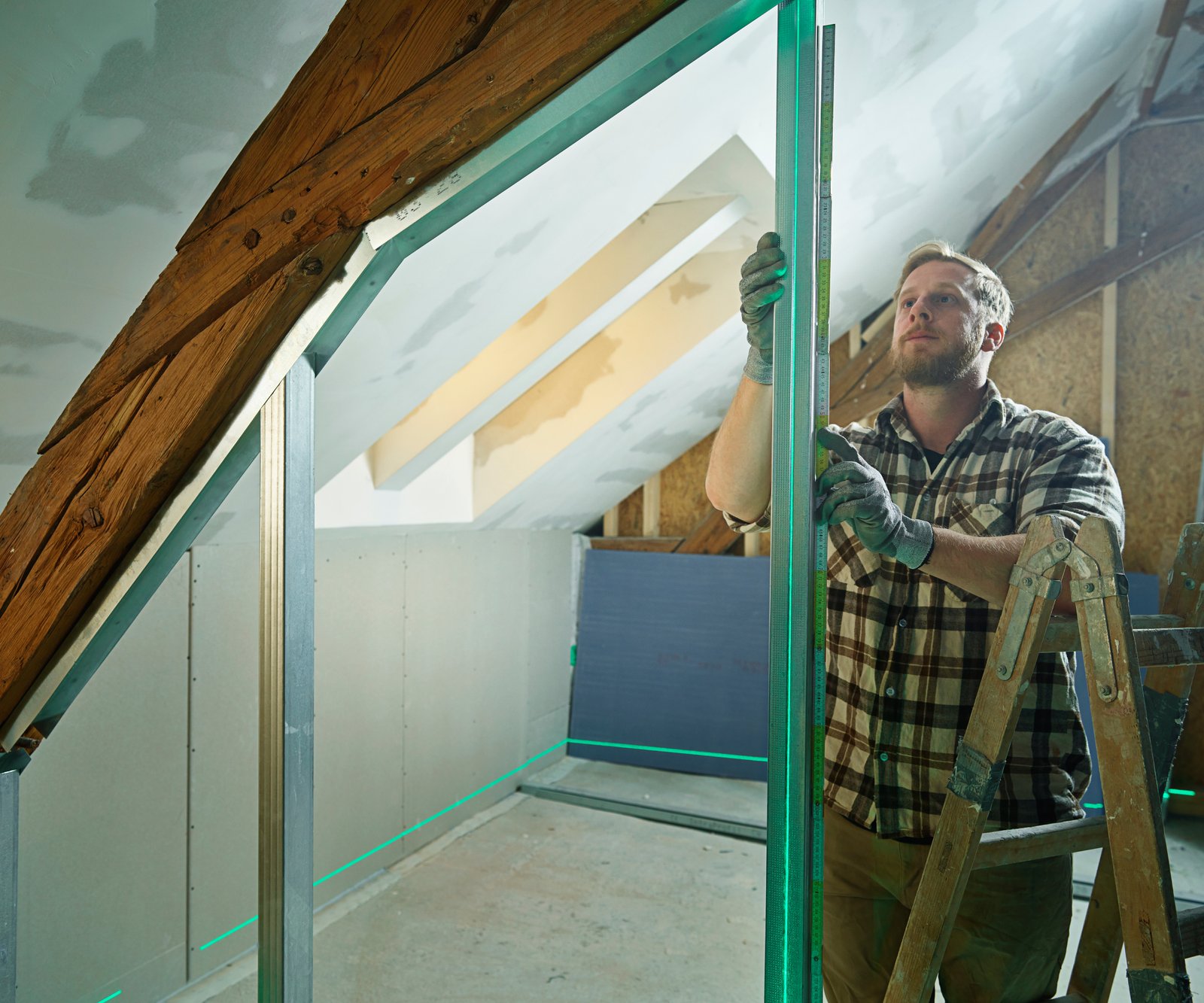 man putting steel frame in place against roof truss