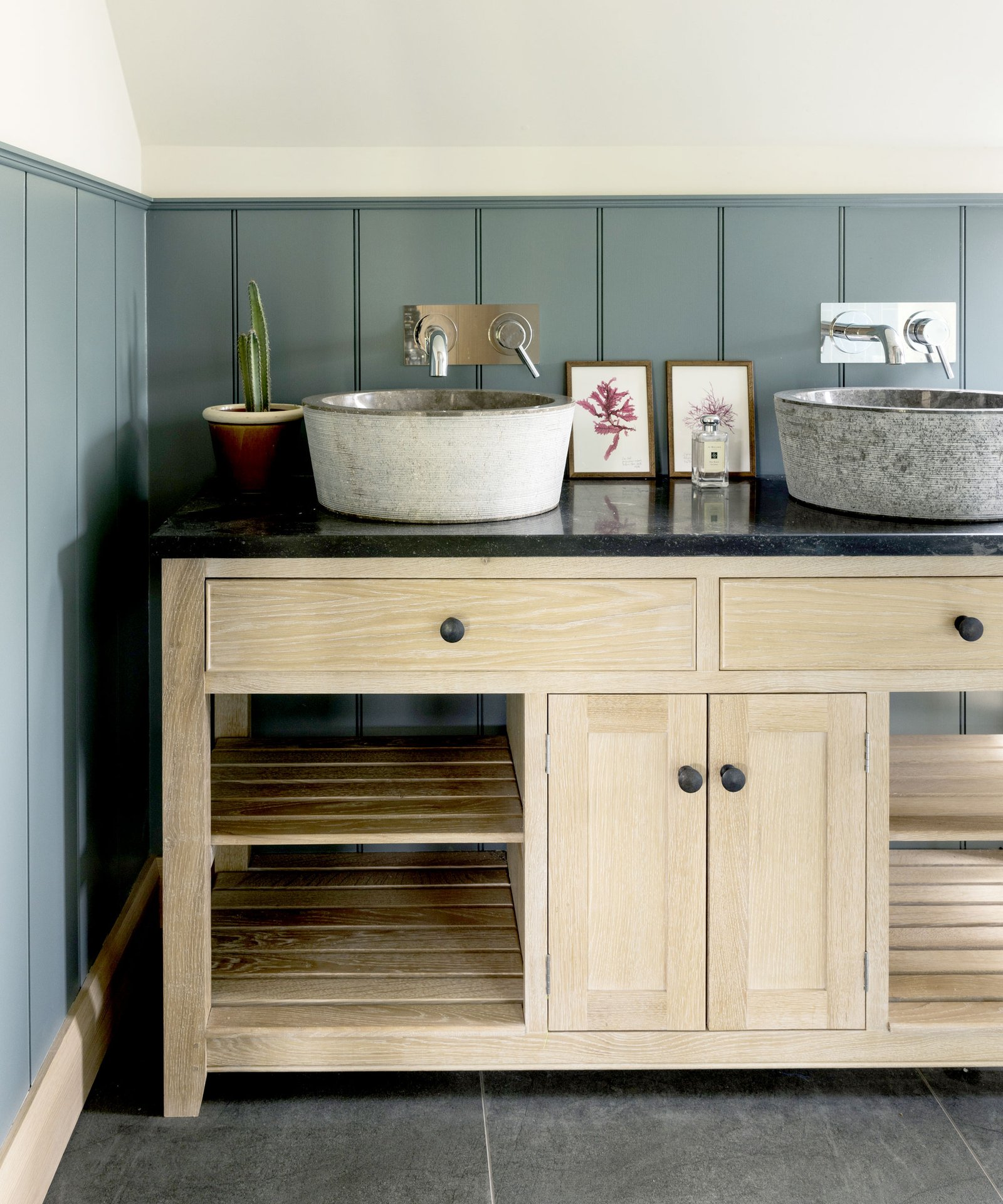 Freestanding wooden sink unit with selves against green panelled wallt