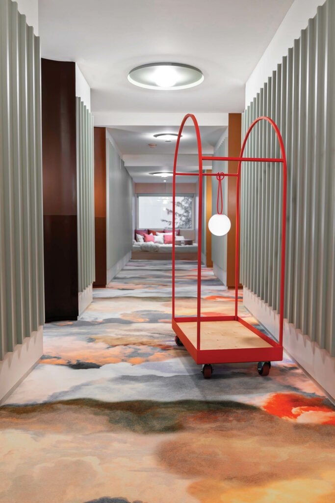 hotel hallway with curved red cart and multicolored carpet