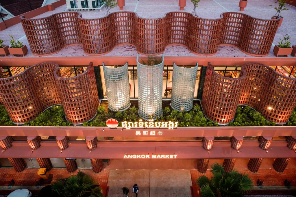 Close-up of Angkor Market’s terracotta façade featuring undulating brise-soleil screens, greenery, and the main entrance with signage