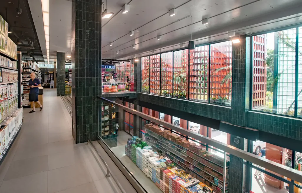 Interior view of Angkor Market with green ceramic tiles, shelves of products, and large glass windows allowing natural light inside