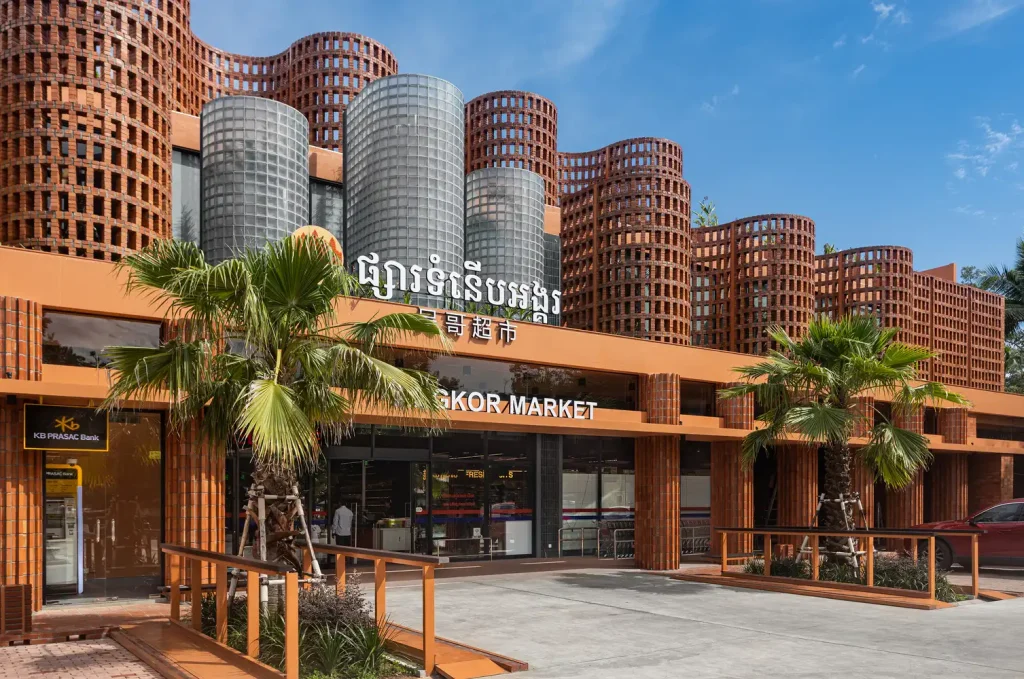 Angkor Market designed by UAD Architects, featuring a side angle view of its brick lattice façade combined with glass cylinders under a bright sky